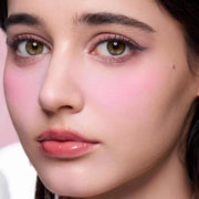 Close-up of a woman wearing Butterfly Cloud Collar matte pink blush and highlighter on cheeks with natural glowing finish