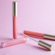 lip gloss collection shiny hydrating long-lasting trendy shades pink tubes with gold caps on pink background