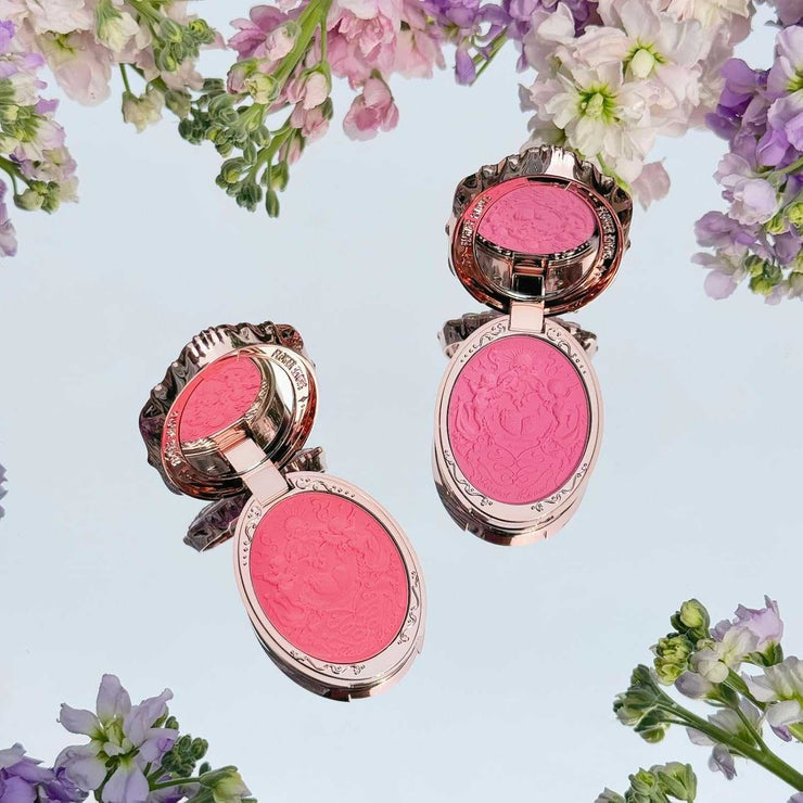 Strawberry Rococo Embossed Blush compact with intricate floral design and silky pink shades surrounded by flowers