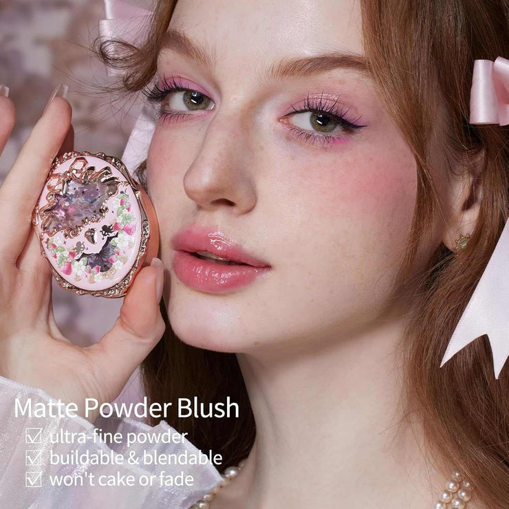close-up of woman with radiant cheeks holding Strawberry Rococo Embossed Blush compact with floral and gemstone design