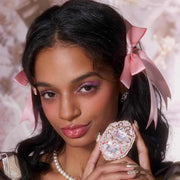 woman with pink makeup and ribbons holding Strawberry Rococo Embossed Blush compact with floral design
