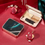 Compact makeup set gift box with eyeshadow palette and applicator on red satin background